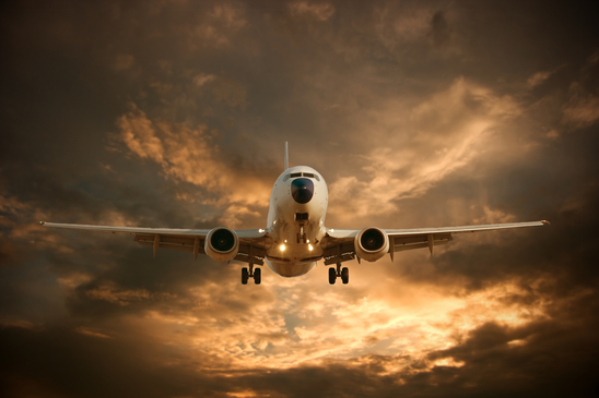 Landing airplane against glowing sky